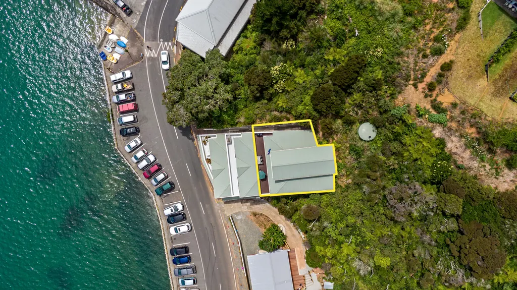 Top-down drone shot of a waterfront property with its boundary outlined in yellow