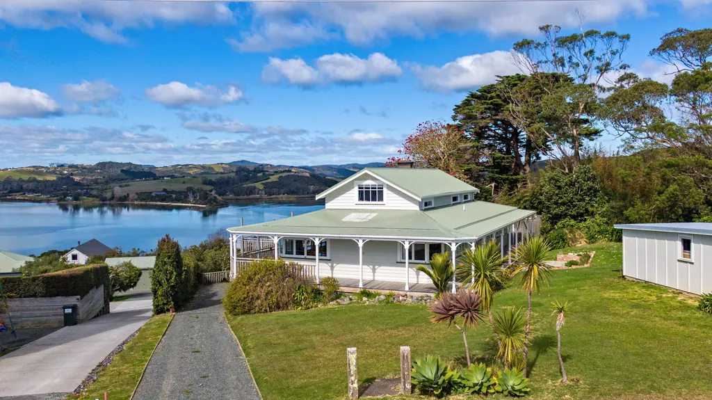 Aerial view of a villa with a wraparound veranda above a harbour and rolling hills