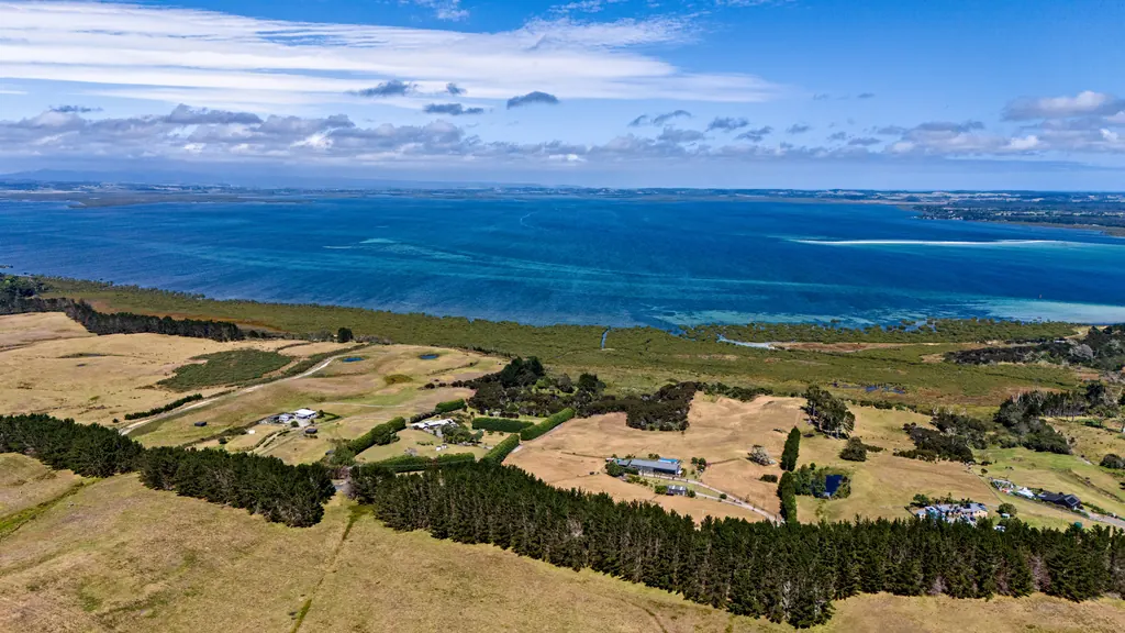 Drone view over farmland to a turquoise bay and distant coastline
